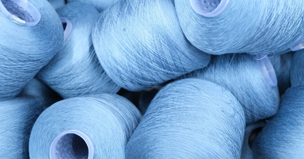 Blue yarn cones representing Dyecon’s advanced thread dyeing technology and denim innovation.